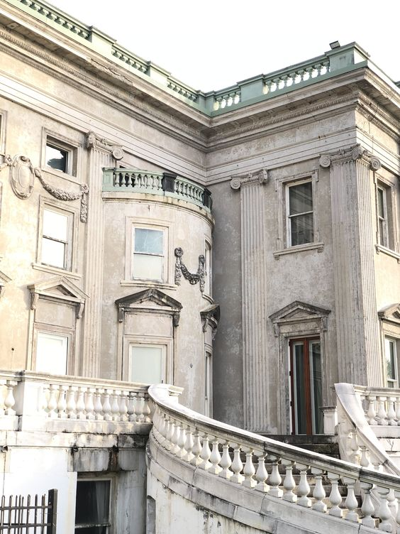 A detail of the rear terrace of Ogden mills Mansion at Staatsburg Historic Site. The building is designed in a Greek Revival style, with an opulent curved staircase, floral swags, and a mint green parapet.