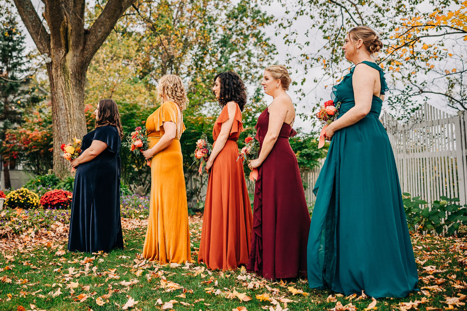 Bridal party in mismatched jewel-tone dresses, standing against a scenic Hudson Valley autumn wedding backdrop