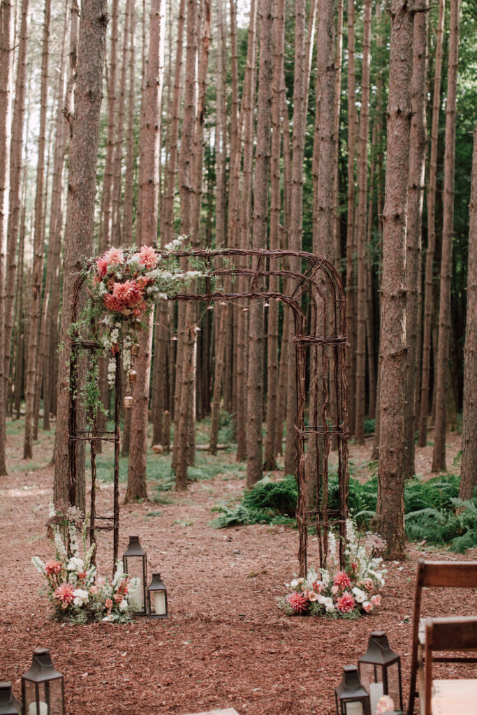 Wicker wedding arch with coral dahlias in the pine grove at Roxbury Barn and Estate