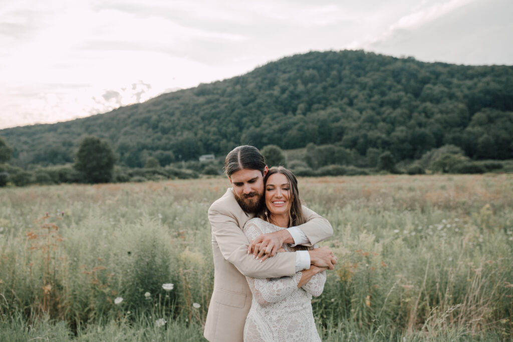 Bride and groom embracing in a wildflower field during their Roxbury Barn and Estate wedding in the Catskills