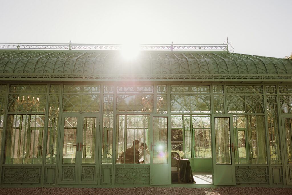 L’Orangerie greenhouse wedding venue in the Hudson Valley, bathed in golden light with green metal and glass architecture.