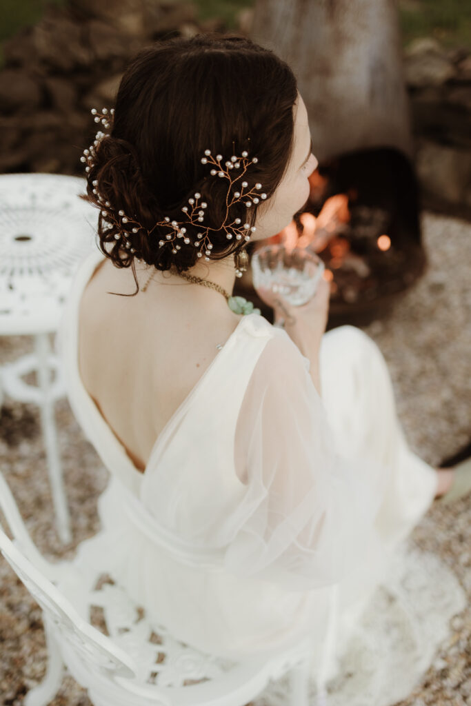 Evening wedding moment with champagne coupe beside a glowing firepit, evoking the intimacy and warmth of a European garden celebration.