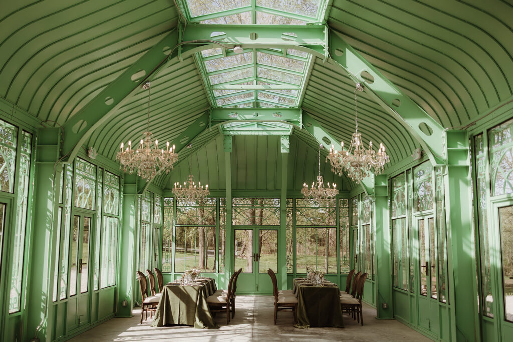 The interior of L'Orangerie, set with long dinner tables beneath soaring crystal chandeliers.