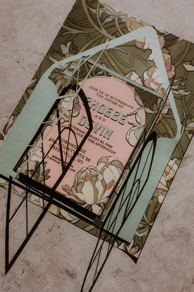 Close-up of custom wooden wedding invitation featuring Mucha-inspired peony artwork and gold ink accents.