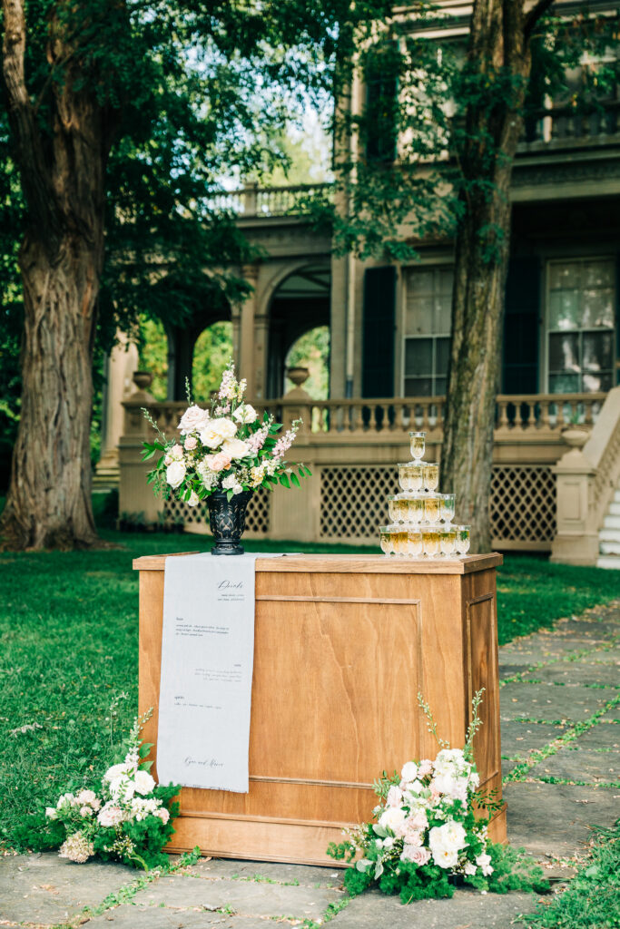 Wood bar draped in blue linen menu with crystal champagne glasses in walkway setting
