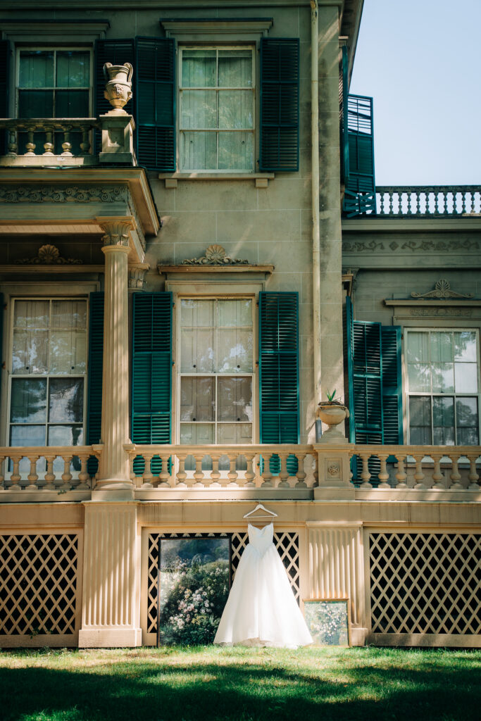Basque-waist wedding gown displayed on the estate terrace with framed floral art backdrop

