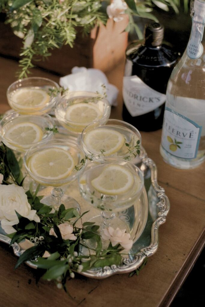 silver tray of coupe glasses with lemons and thyme garnish